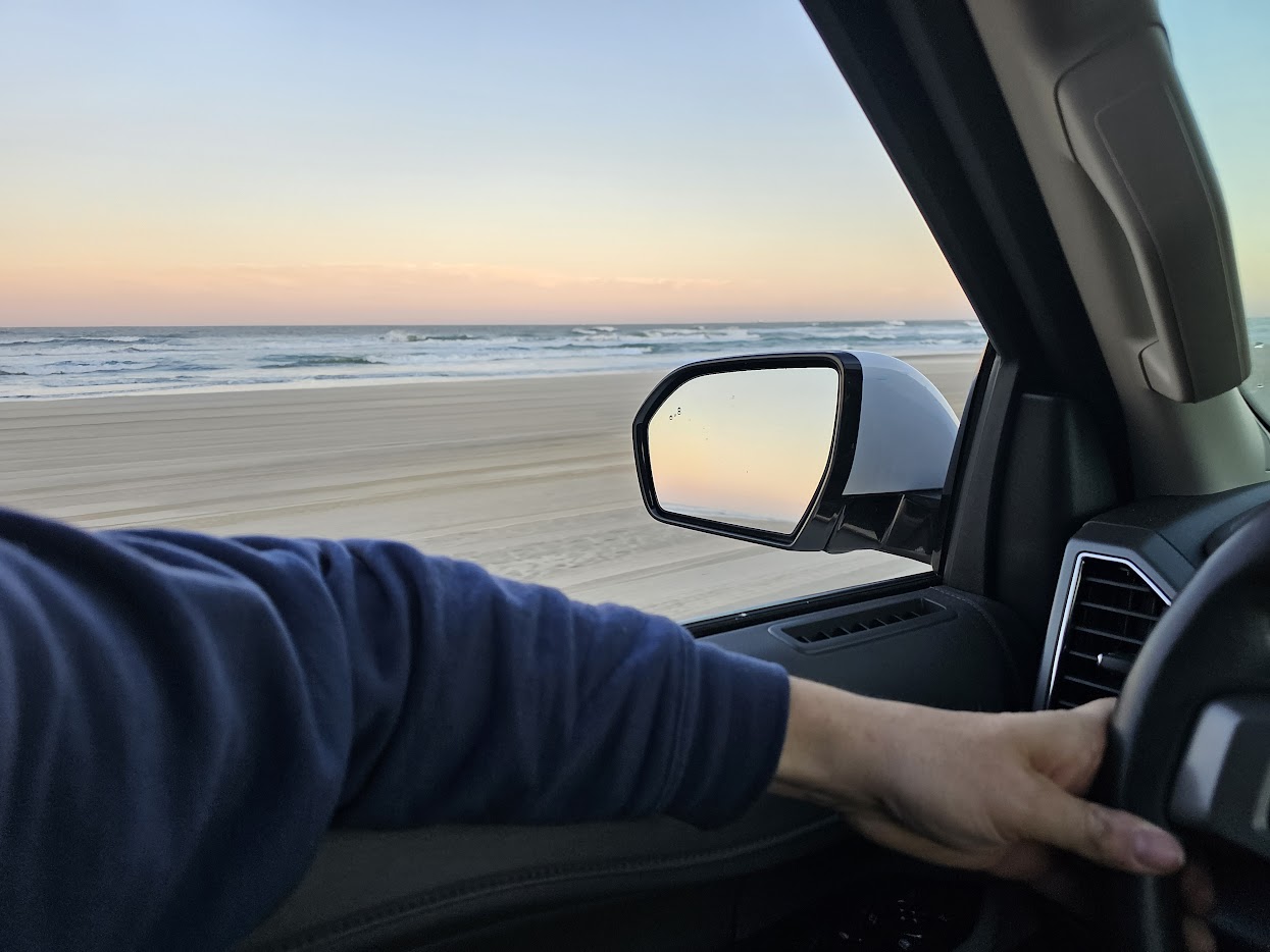Vehicle driving on Carova beach at sunset
