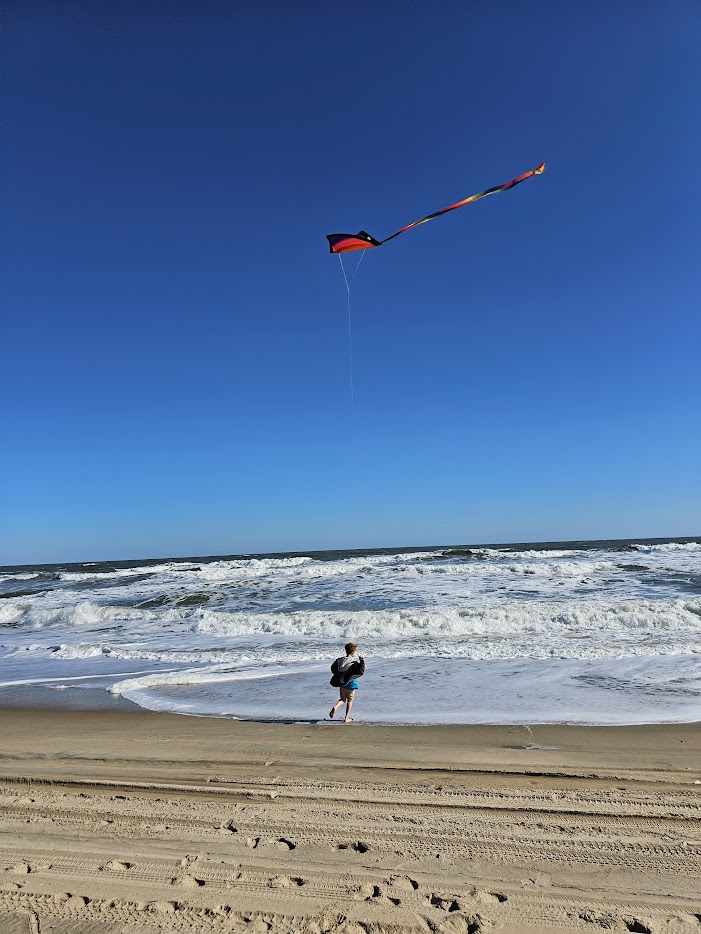 Kid flying a kite on the beach in fall